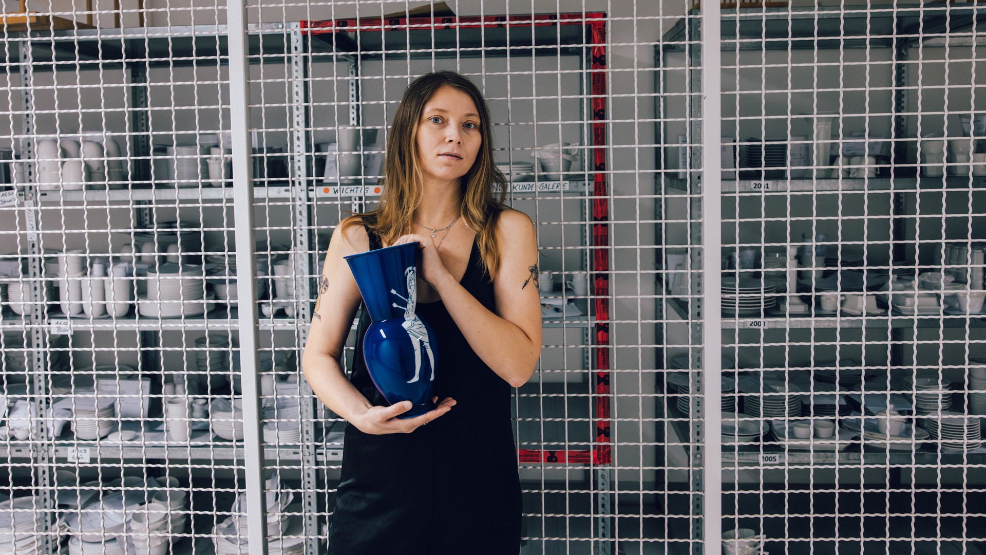 Julia Beliaeva, die eine blaue Vase in einem Lagerraum hält.